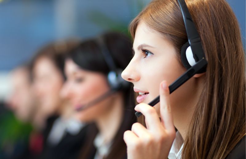 Agente de atención al cliente usando auriculares mientras atiende llamadas en un centro de soporte.